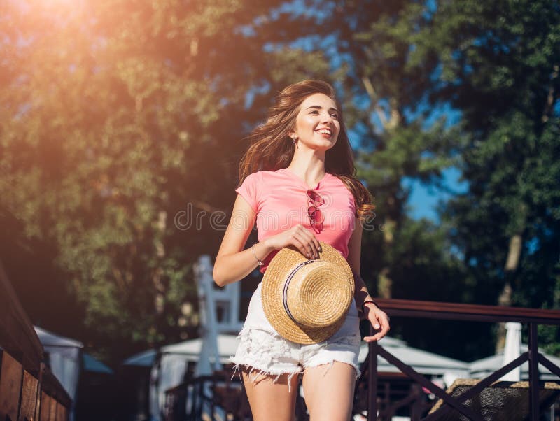 Amazing joyful pretty girl with long brunette hair. having fun on the beach, dancing and smiling, vacation mood.Nice laughing girl in hat. Amazing joyful pretty girl with long brunette hair. having fun on the beach, dancing and smiling, vacation mood.Nice laughing girl in hat.