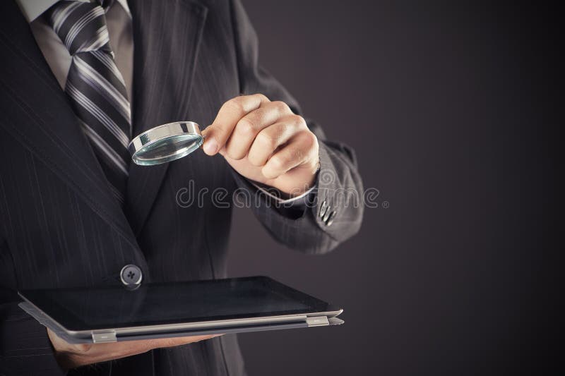 Het vergrootglas en de tablet van de zakenmanholding stock fotografie Het vergrootglas en de tablet van de zakenmanholding stock fotografie
