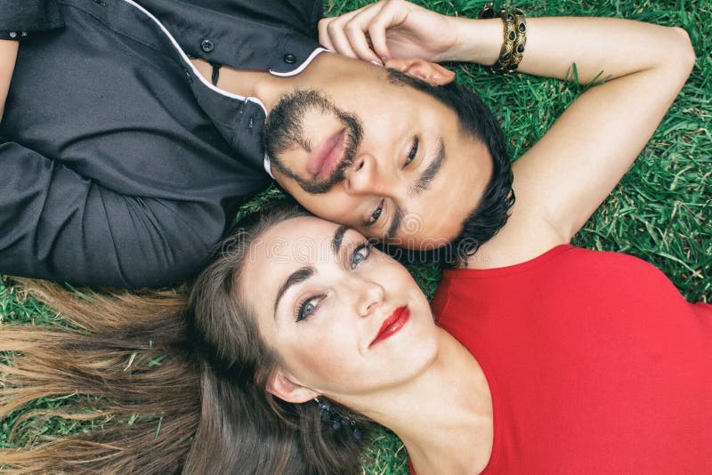 Het verhaal van de liefde Een donkerbruine man en een mooie donkerbruine vrouw liggen op het gras royalty-vrije stock afbeelding Het verhaal van de liefde Een donkerbruine man en een mooie donkerbruine vrouw liggen op het gras royalty-vrije stock afbeelding