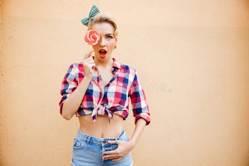 Het verraste leuke pinupmeisje behandelde haar oog door lolly royalty-vrije stock foto Het verraste leuke pinupmeisje behandelde haar oog door lolly royalty-vrije stock foto