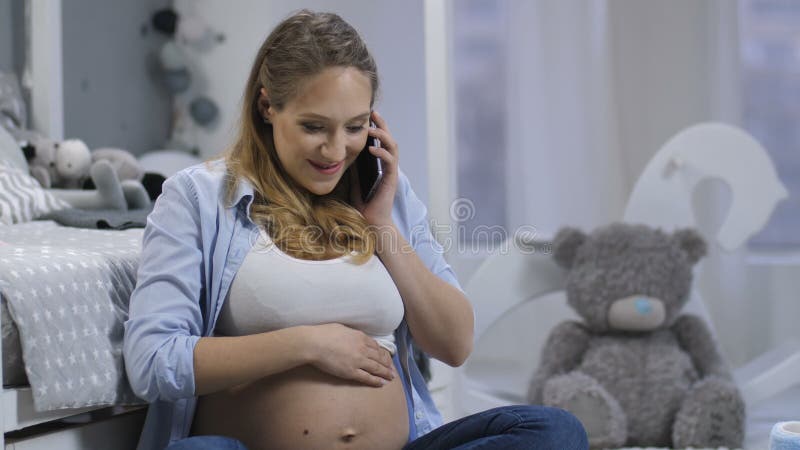 Het verwachten van mamma die op cellphone als babyduwen spreken