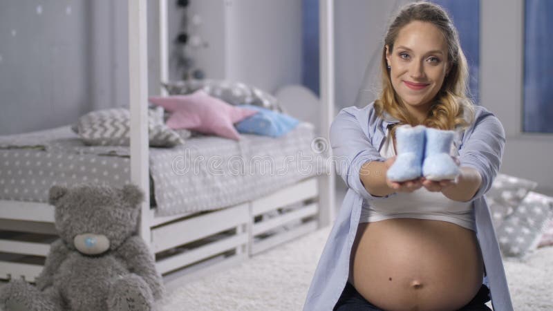 Het verwachten van mamma die zuigelingsschoenen aanbieden aan camera