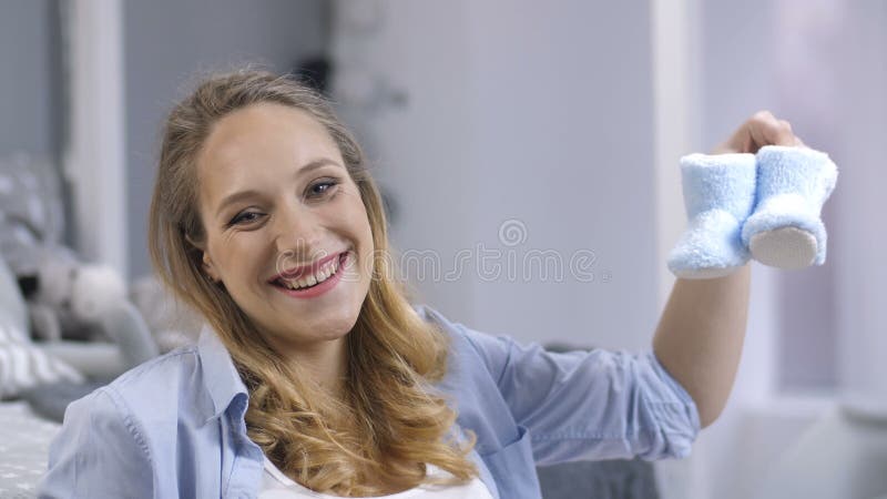 Het verwachten van mamma het schudden babyschoenen en het glimlachen