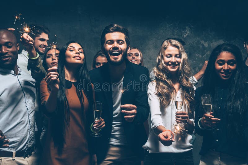 Group of cheerful young people carrying sparklers and champagne flutes. Group of cheerful young people carrying sparklers and champagne flutes