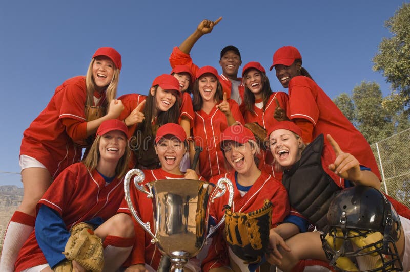 Het Vieren van softballteam and coach with trophy tegen Hemel stock afbeelding Het Vieren van softballteam and coach with trophy tegen Hemel stock afbeelding