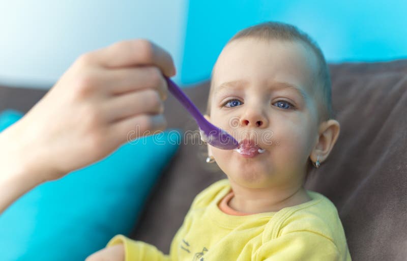 Het voeden van Haar Babymeisje met een Lepel royalty-vrije stock foto Het voeden van Haar Babymeisje met een Lepel royalty-vrije stock foto