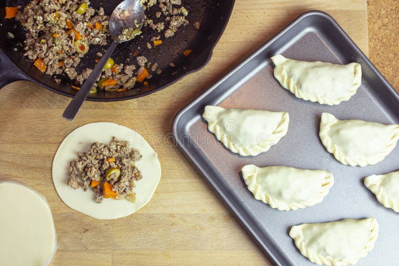 Het voorbereiden van Argentijnse Empanadas met Rundergehakt die en voor Oven Baking vullen vormen royalty-vrije stock afbeelding Het voorbereiden van Argentijnse Empanadas met Rundergehakt die en voor Oven Baking vullen vormen royalty-vrije stock afbeelding