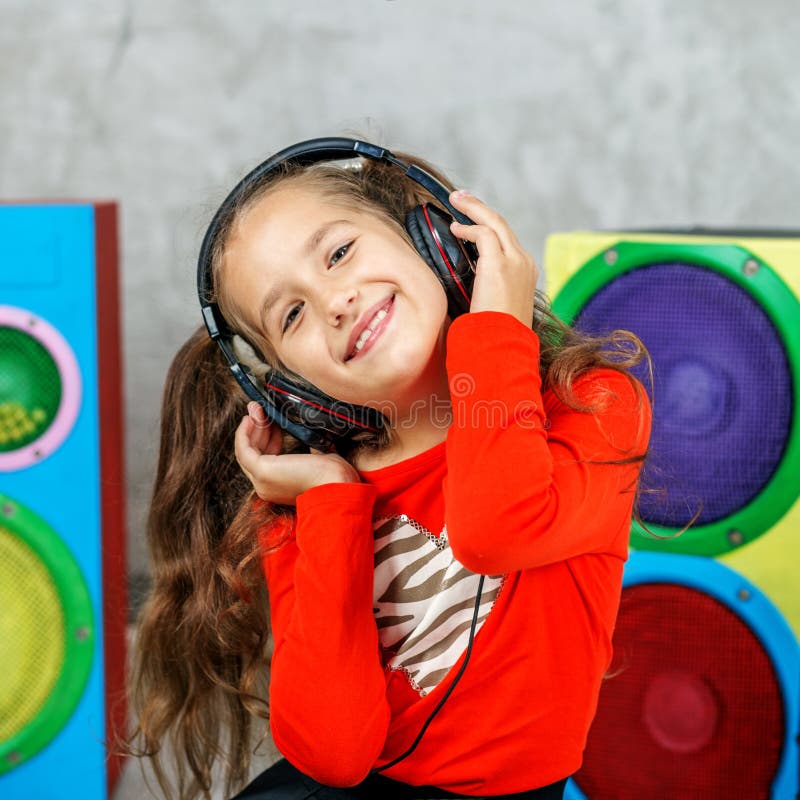 Het vrolijke kindmeisje luistert aan een lied met hoofdtelefoons vierkant C stock foto's Het vrolijke kindmeisje luistert aan een lied met hoofdtelefoons vierkant C stock foto's
