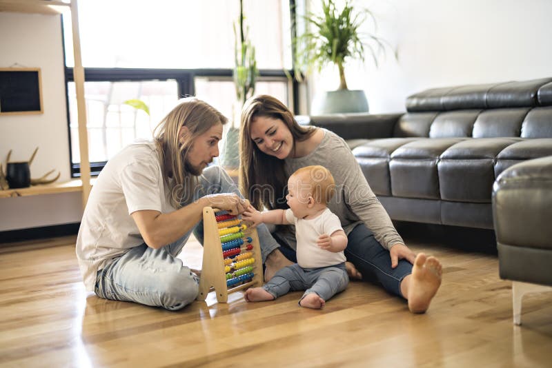 Het vrolijke ouder spelen met zijn babymeisje op vloer bij woonkamer stock fotografie Het vrolijke ouder spelen met zijn babymeisje op vloer bij woonkamer stock fotografie