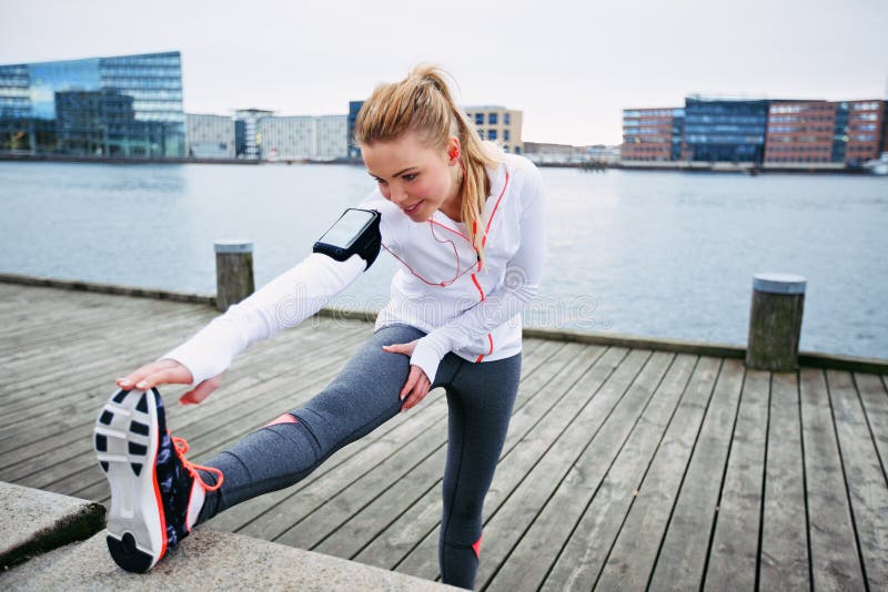 Fit young woman stretching before a run. Young female runner stretching her muscles before a training session. Fit young woman stretching before a run. Young female runner stretching her muscles before a training session