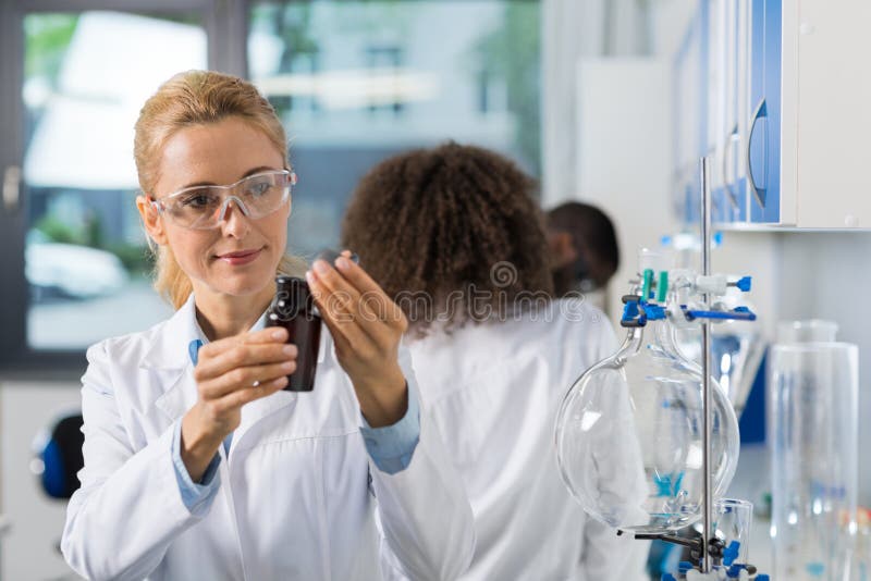 Het vrouwelijke Wetenschappelijke Onderzoek van Onderzoekersin laboratory doing, Vrouw die met Chemische producten over Groep Wet royalty-vrije stock fotografie Het vrouwelijke Wetenschappelijke Onderzoek van Onderzoekersin laboratory doing, Vrouw die met Chemische producten over Groep Wet royalty-vrije stock fotografie