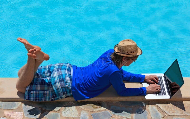Het werken aan laptop bij de pool royalty-vrije stock afbeelding Het werken aan laptop bij de pool royalty-vrije stock afbeelding