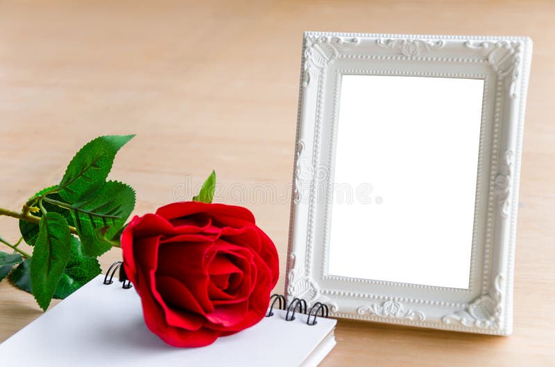 White vintage photo frame and red rose with blank diary on wooden background. clipping path. White vintage photo frame and red rose with blank diary on wooden background. clipping path.
