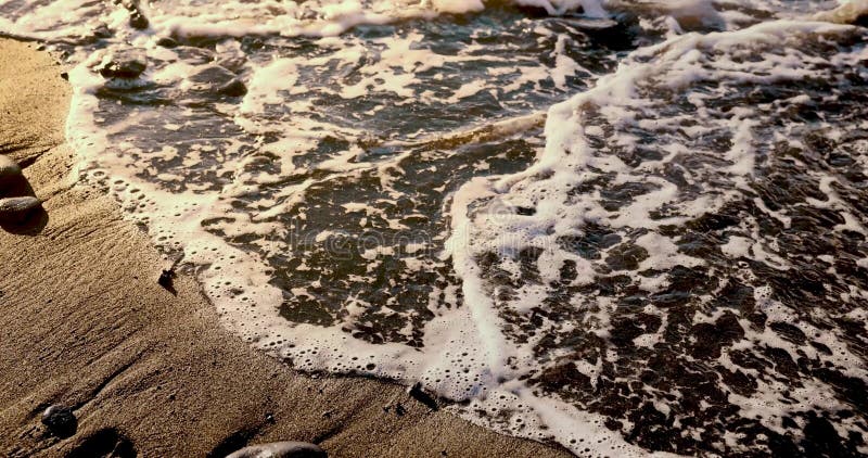 Het woord tenerife wordt verwijderd door de oceaangolf op het strand van vulkaan zwart zand