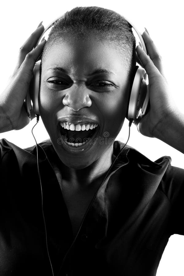 Black and white portrait of beautiful young black woman, listening to music on headphones, and singing along. Black and white portrait of beautiful young black woman, listening to music on headphones, and singing along.