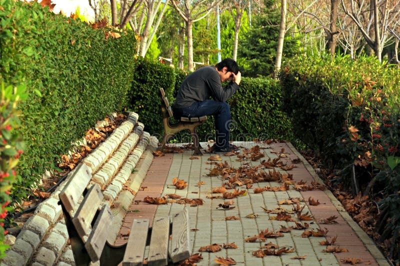 Het zitten alleen in het park in de herfst droevige jongelui stock afbeeldingen Het zitten alleen in het park in de herfst droevige jongelui stock afbeeldingen