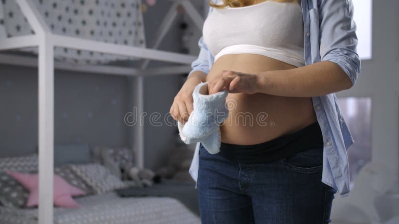 Het zwangere moeder spelen met leuke babyschoenen