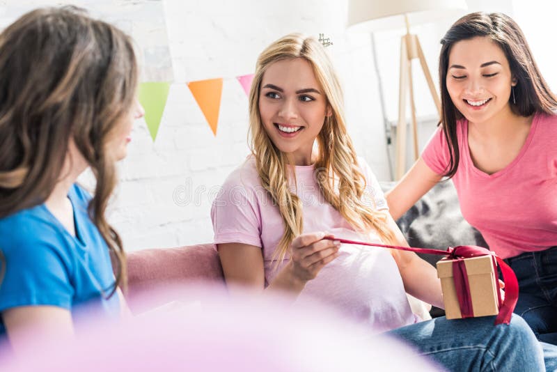 het zwangere vrouw openen huidig van multiculturele vrienden bij baby stock fotografie het zwangere vrouw openen huidig van multiculturele vrienden bij baby stock fotografie