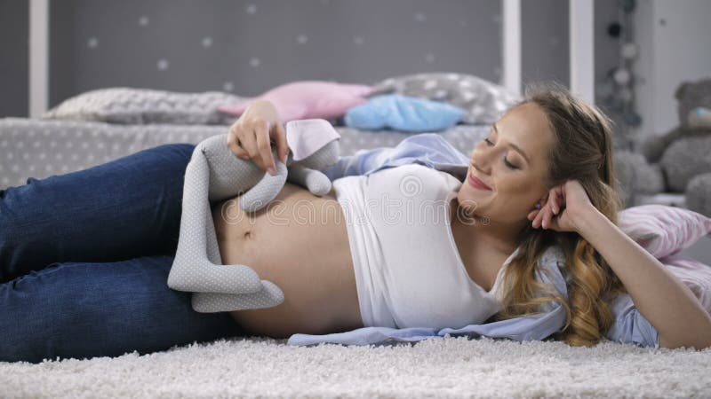 Het zwangere vrouw spelen met babystuk speelgoed konijn