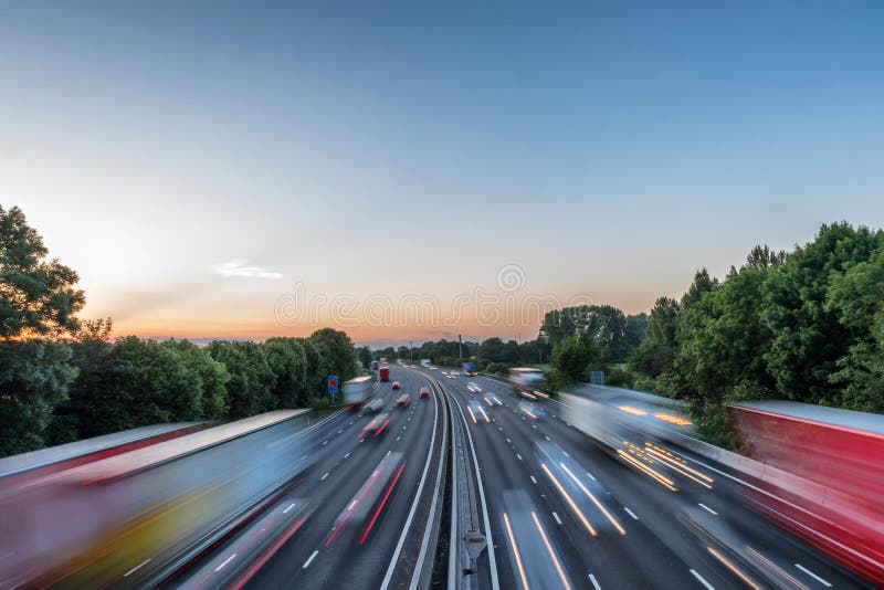 Het zware verkeer die van de zonsondergangmening zich bij snelheid op Britse autosnelweg in Engeland bewegen