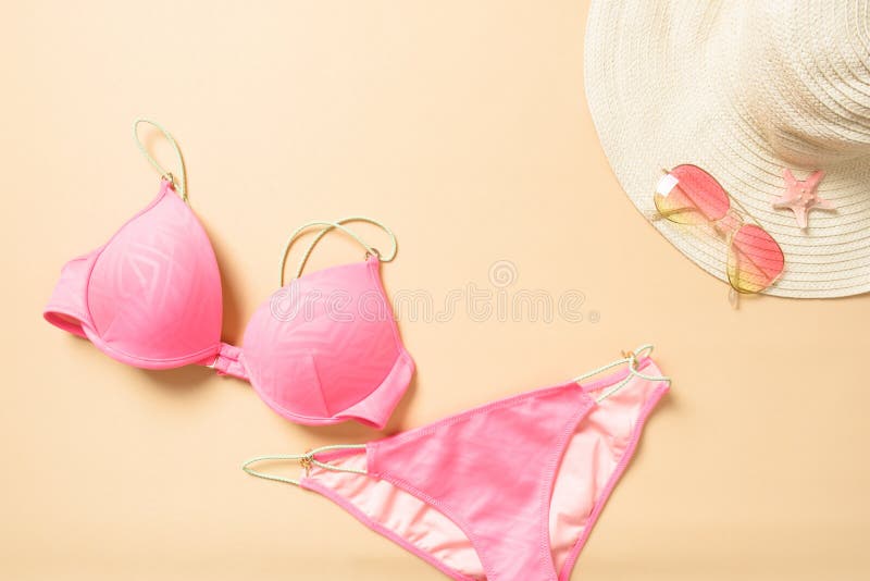 Pink women`s swimsuit, straw hat and sunglasses on yellow summer background. Flat lay fashion girl`s outfit and beach accessories. Top view feminine summer stuff. Summer vacation, holiday concept. Pink women`s swimsuit, straw hat and sunglasses on yellow summer background. Flat lay fashion girl`s outfit and beach accessories. Top view feminine summer stuff. Summer vacation, holiday concept