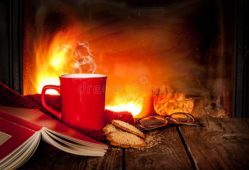 Hete thee of koffie in een rode mok, een boek en een open haard stock afbeeldingen Hete thee of koffie in een rode mok, een boek en een open haard stock afbeeldingen