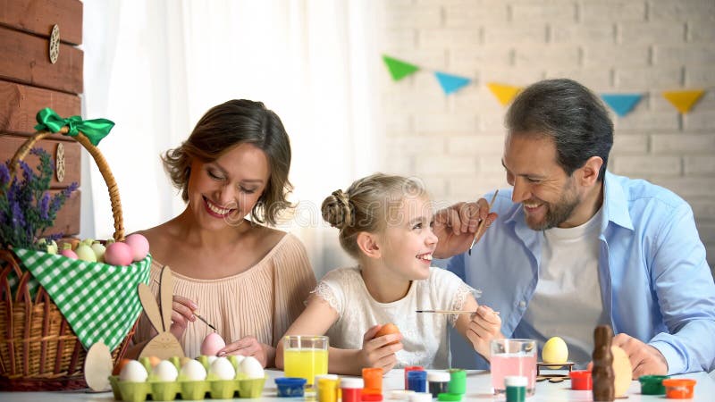 Heureuse famille décorant des oeufs de pâques, temps heureux ensemble, souvenirs durables photo libre de droits