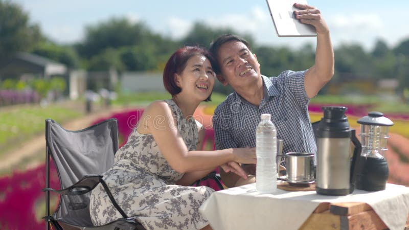 Heureux couple d'âge moyen selfie ensemble pendant détendu assis dans le jardin fleuri clips vidéos