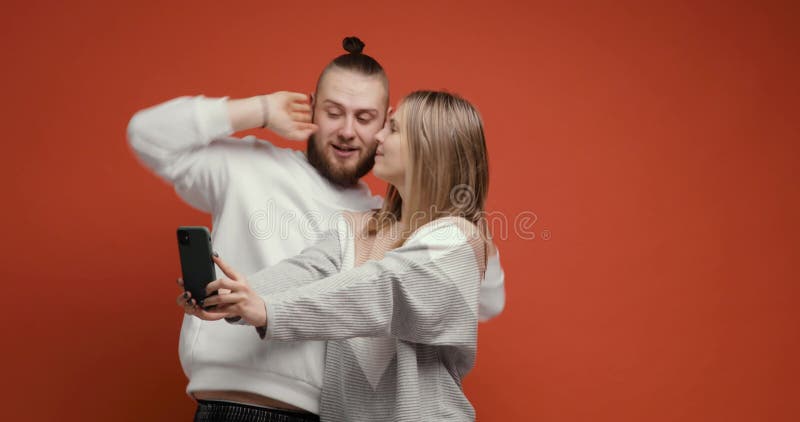 Heureux couple femme homme faisant selfie ensemble en utilisant smartphone sur fond rouge. clips vidéos