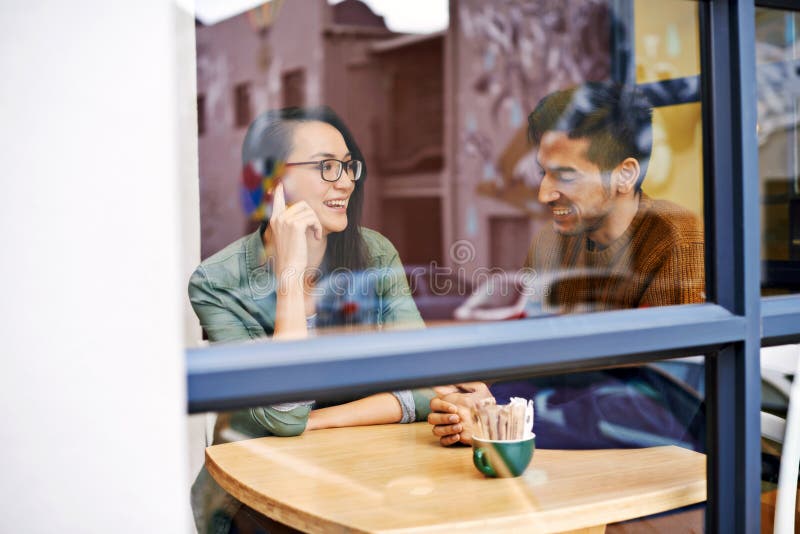 Happy couple, relax and enjoying cafe with date for conversation, bonding or romance at indoor restaurant. Man and women with smile by window at coffee shop for social, talking or chatting at table. Happy couple, relax and enjoying cafe with date for conversation, bonding or romance at indoor restaurant. Man and women with smile by window at coffee shop for social, talking or chatting at table.