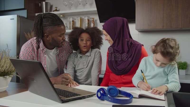 Heureux divers parents multiethniques avec deux petites filles mignonnes profiter des loisirs cuisine domestique banque de vidéos