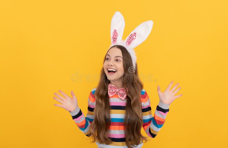 Heureux enfant de pâques dans les oreilles de lapin et noeud d'arc sur fond jaune photo libre de droits