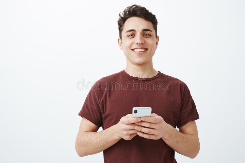 Heureux pour avoir de grands amis en ligne Modèle masculin heureux beau dans l'équipement occasionnel, tenant le smartphone et re images stock Heureux pour avoir de grands amis en ligne Modèle masculin heureux beau dans l'équipement occasionnel, tenant le smartphone et re images stock