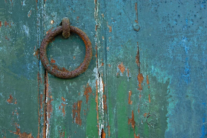 A rusty door knocker on a green weathered door. A rusty door knocker on a green weathered door.