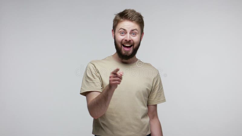 Hey, te necesitamos! alegre hombre barbudo sonriente riéndose despreocupado y señalando a la cámara escogiendo almacen de metraje de vídeo
