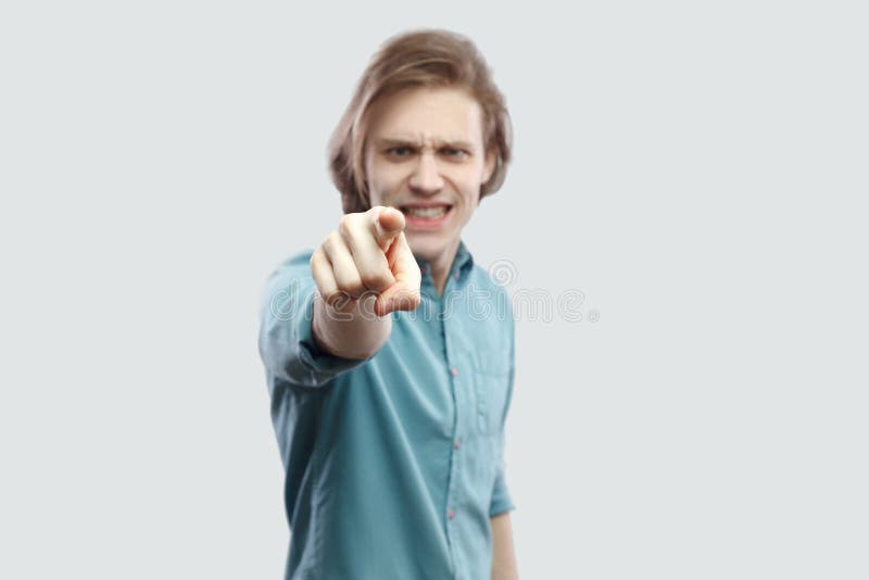 Hey you. Portrait of serious blame handsome long haired blonde young man in blue casual shirt standing, pointing, alarming and