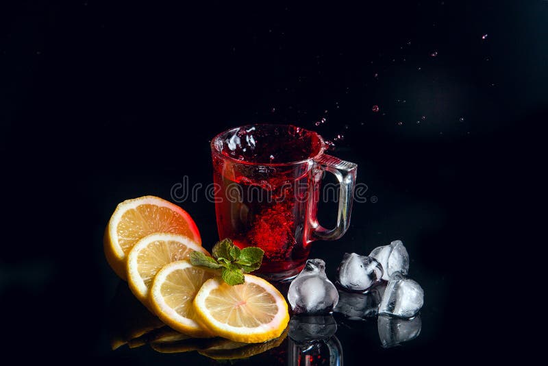 Hibiscus cold tea splash from the fallen ice cube into glass with beverage isolated on black background royalty free stock photography Hibiscus cold tea splash from the fallen ice cube into glass with beverage isolated on black background royalty free stock photography