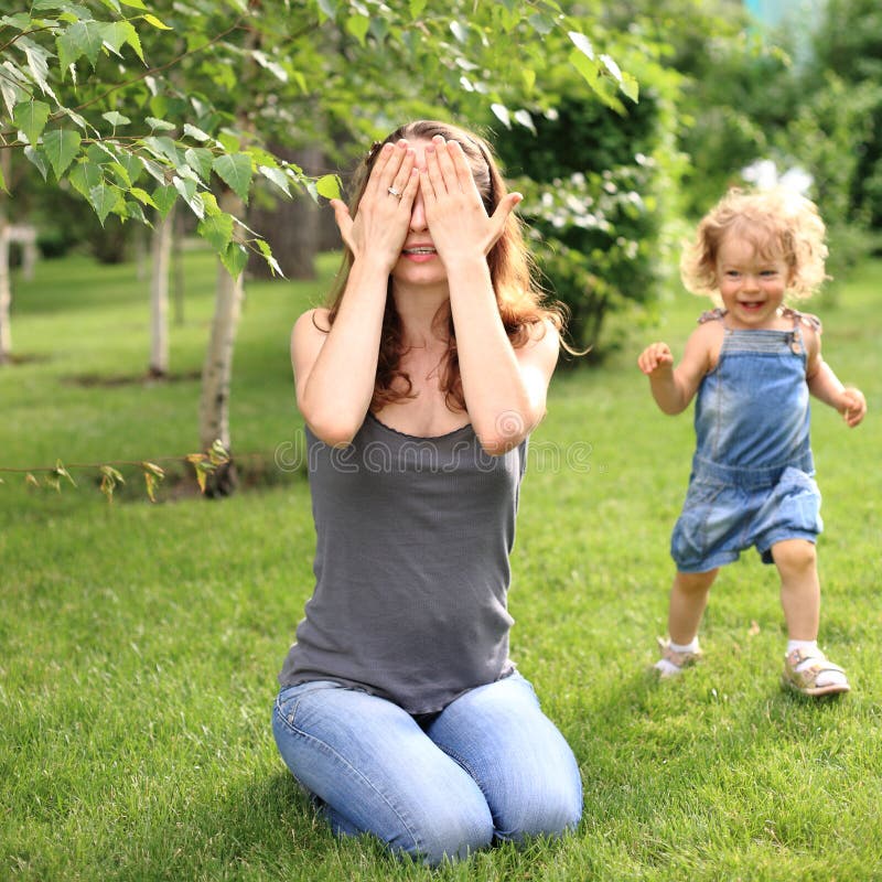 Woman and child playing hide and seek in summer park