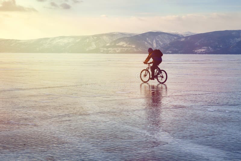 Hiele al viajero del motorista con las mochilas en la bici en el hielo del lago Baikal Contra la perspectiva del cielo de la pues imagen de archivo Hiele al viajero del motorista con las mochilas en la bici en el hielo del lago Baikal Contra la perspectiva del cielo de la pues imagen de archivo