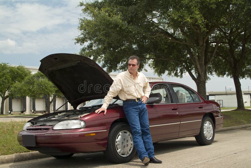 An annoyed man, who is apparently experiencing car trouble, waiting for a tow truck or assistance of some sort. An annoyed man, who is apparently experiencing car trouble, waiting for a tow truck or assistance of some sort.