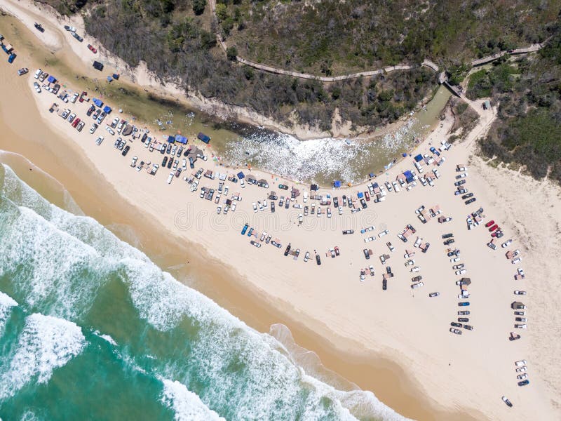 High angle aerial bird`s eye drone view of four-wheel drive cars parked at Eli Creek, a river mouth with crystal clear water
