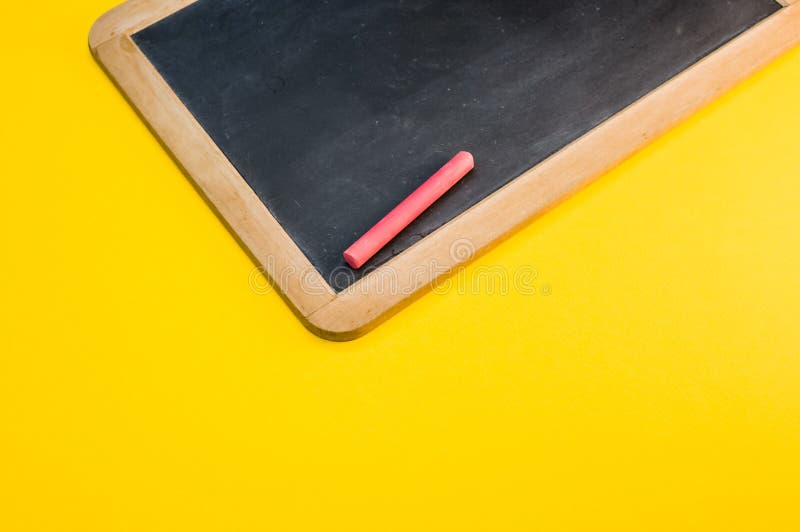 High Angle Closeup of a Blackboard with Chalks on a Yellow Surface