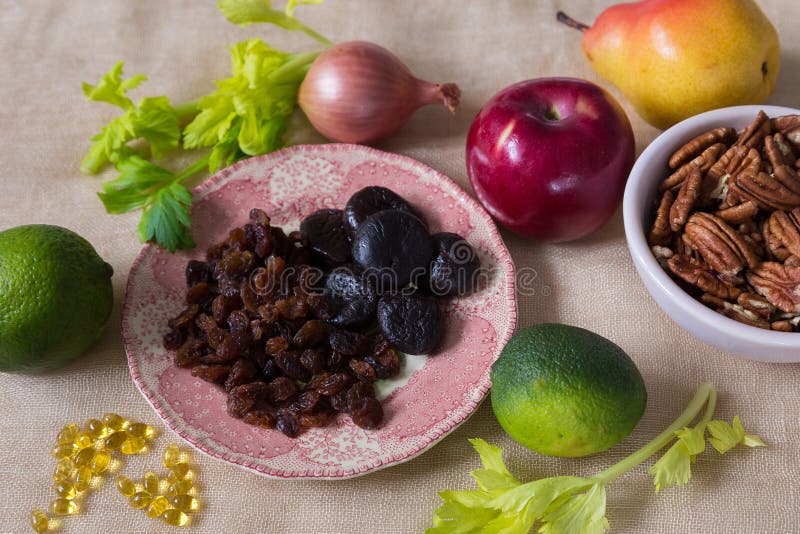 High angle selective focus still life of healthy foods, including dried figs and raisins in a small pink plate