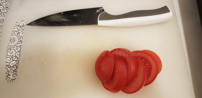 High angle shot of chopped tomatoes and a knife on a white chopping board stock image High angle shot of chopped tomatoes and a knife on a white chopping board stock image