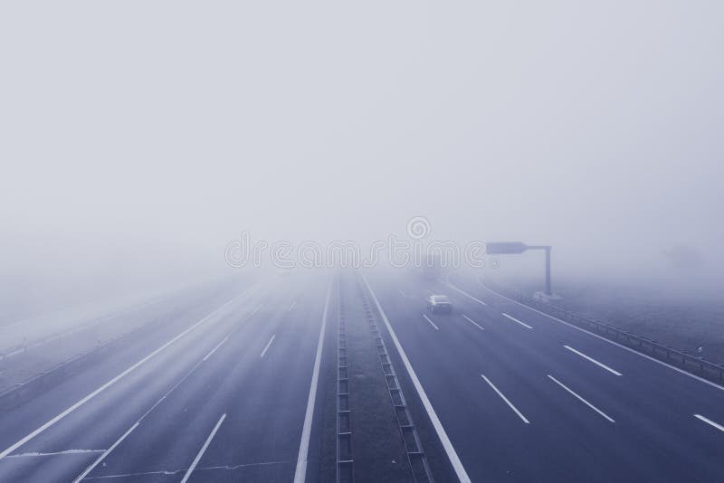 High angle shot of a highway covered in fog with cars in the early morning.