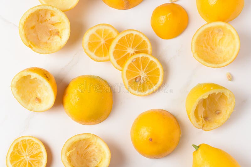 High angle shot of lemon rinds, whole lemons and lemon slices on a white marble kitchen surface stock photos