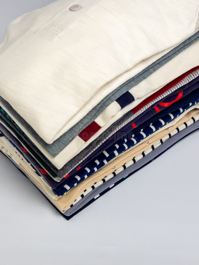 Stacked folded shirts in various colors and patterns on a clean white background royalty free stock photo