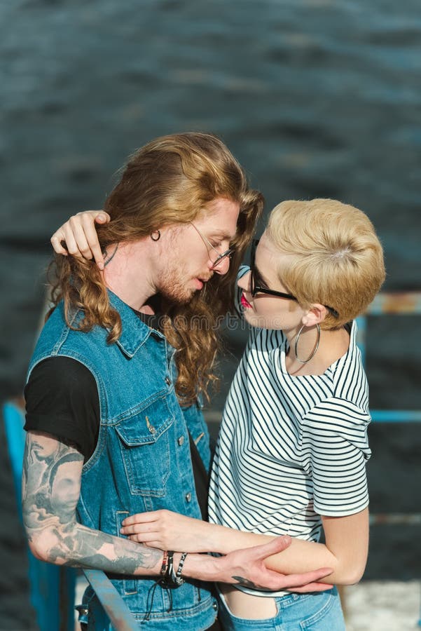 boyfriend with tattoos and stylish girlfriend standing with bicycle on  bridge and looking away Stock Photo | Adobe Stock
