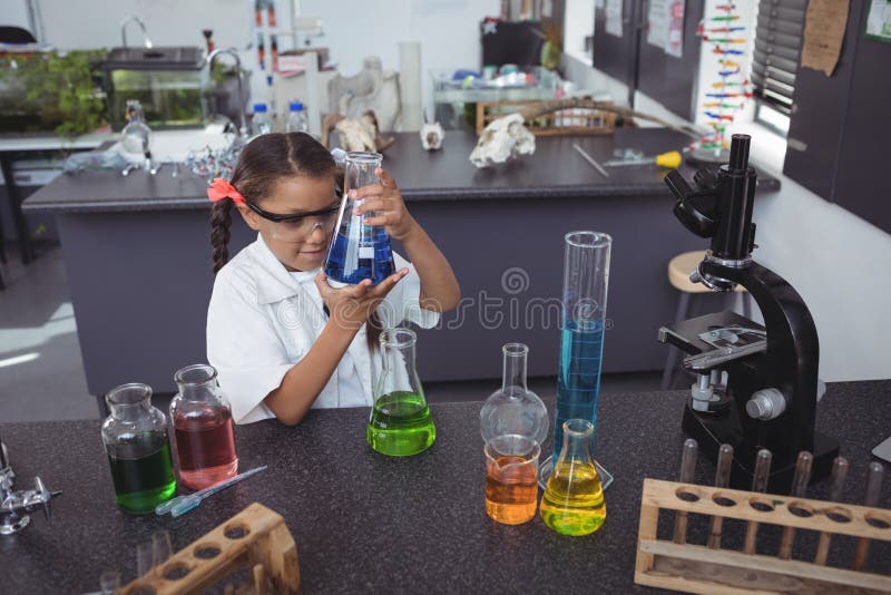 High angle view of elementary student examining blue chemical in flask at laboratory royalty free stock photo