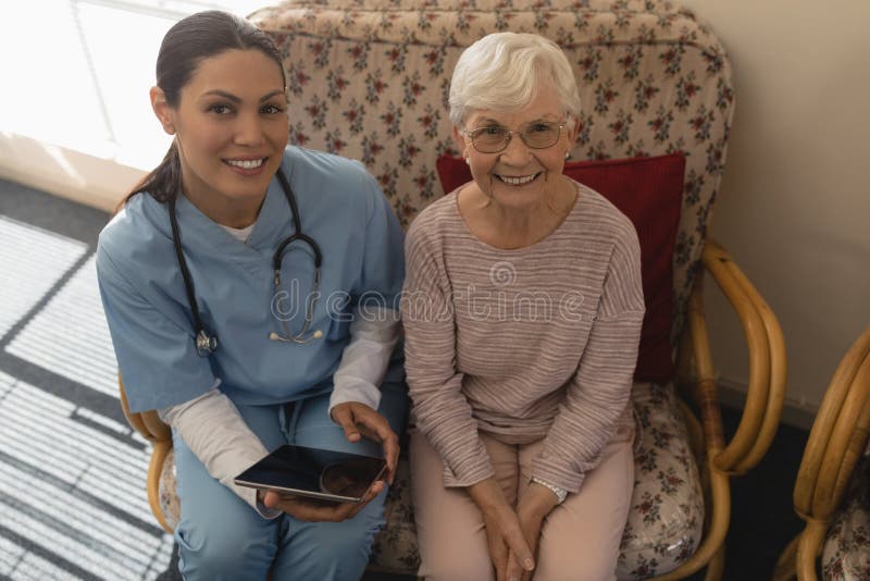 High angle view of female doctor and senior woman looking at camera stock photo High angle view of female doctor and senior woman looking at camera stock photo